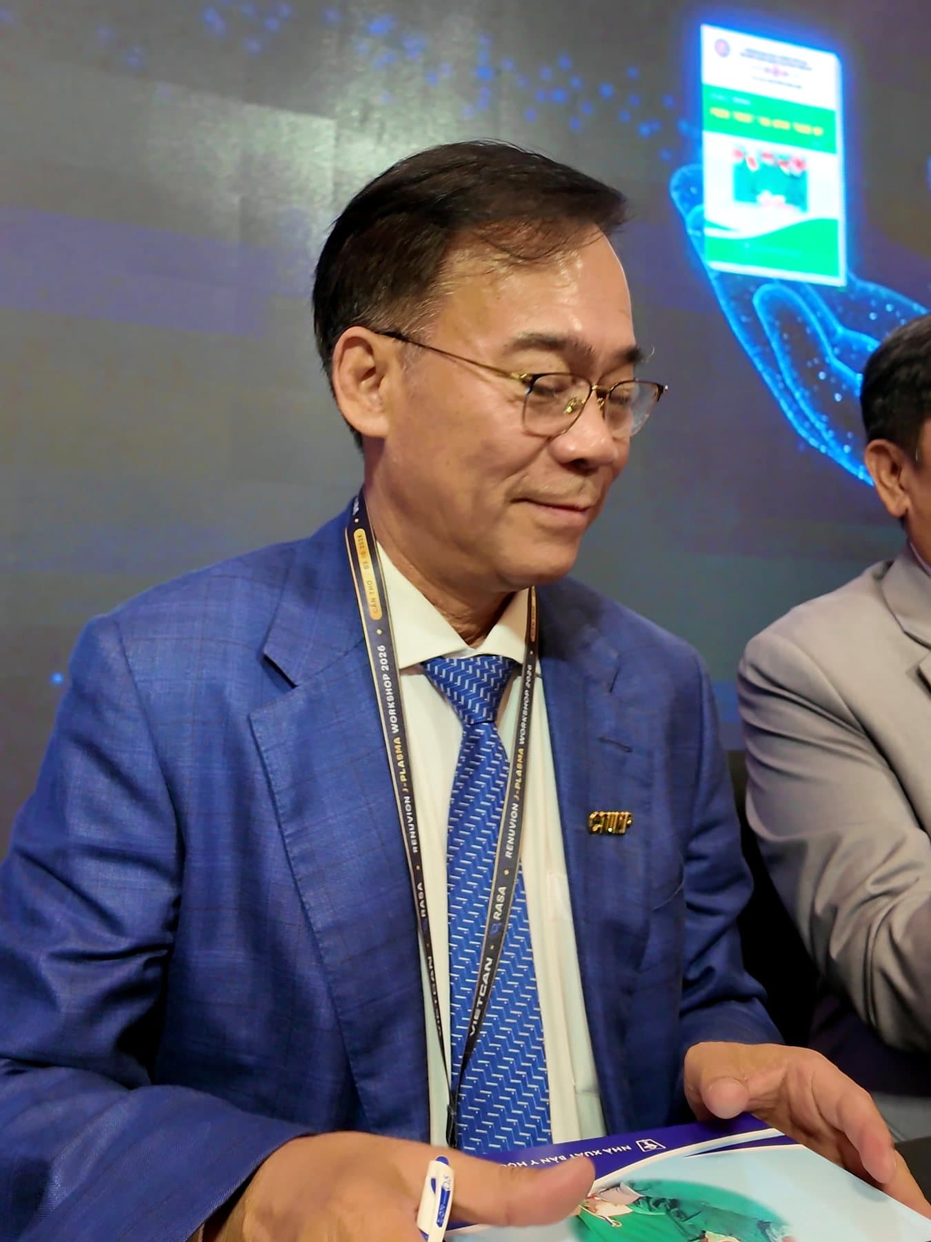 Assoc. Prof. Nguyen Van Lam handing a signed copy to a delegate
