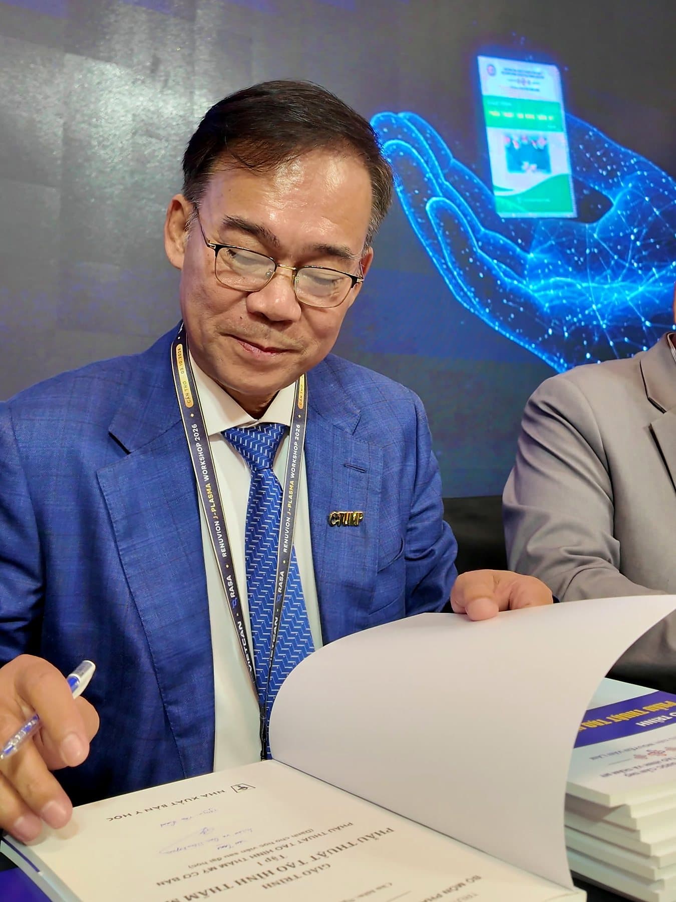 Assoc. Prof. Nguyen Van Lam signing the title page of a volume
